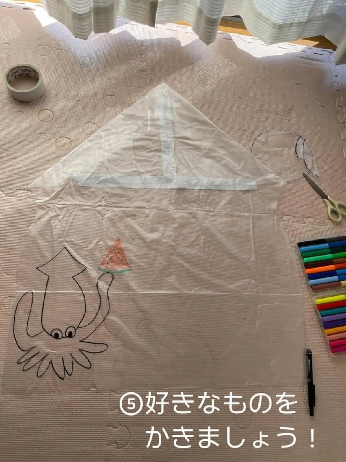 ゴミ袋の左下に、黒いペンで描いたイカと、色を塗った小さなスイカの絵がある。