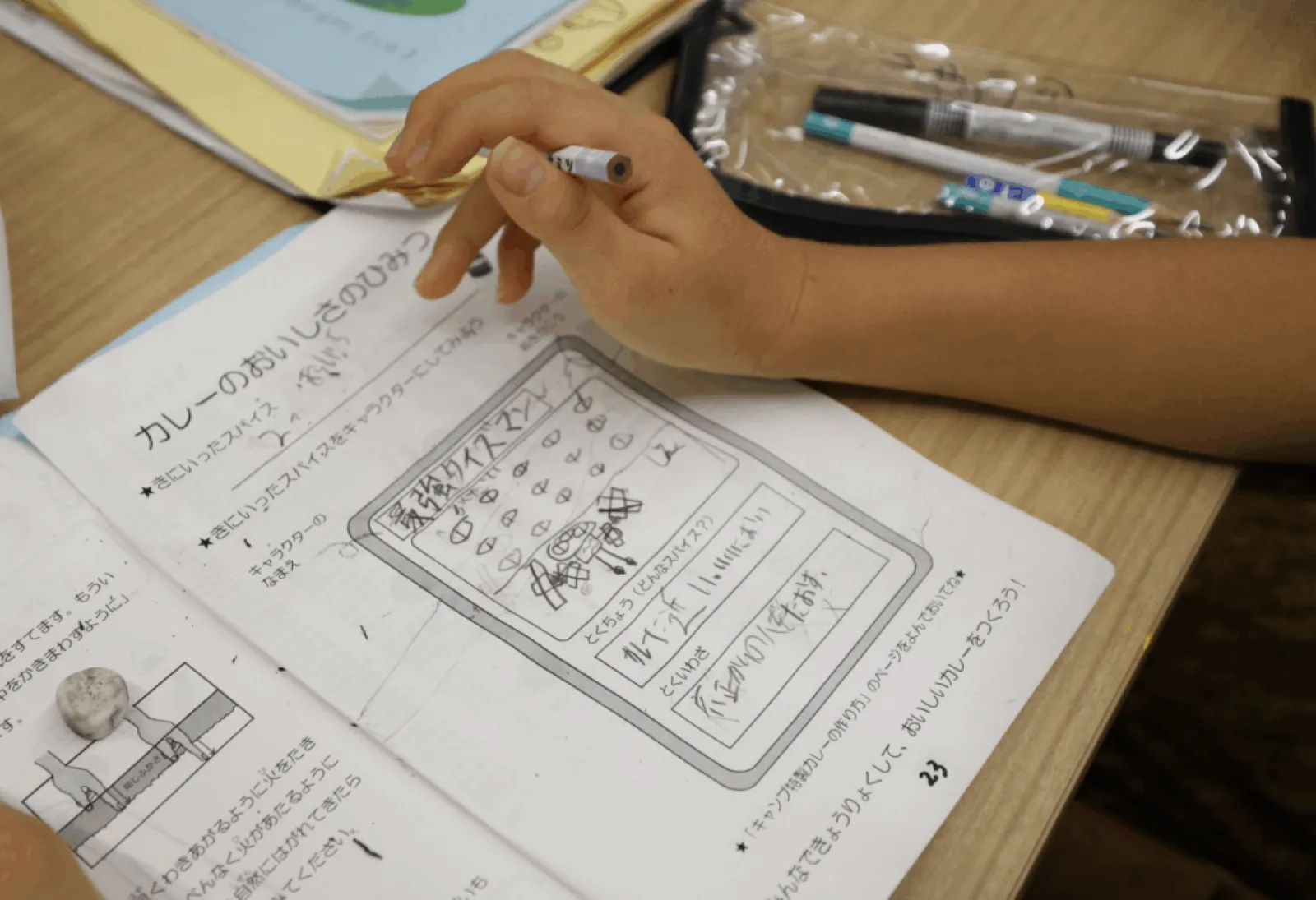 「カレーのおいしさのひみつ」のワークシートに、子どもが鉛筆でスパイスのキャラクターを描いている。