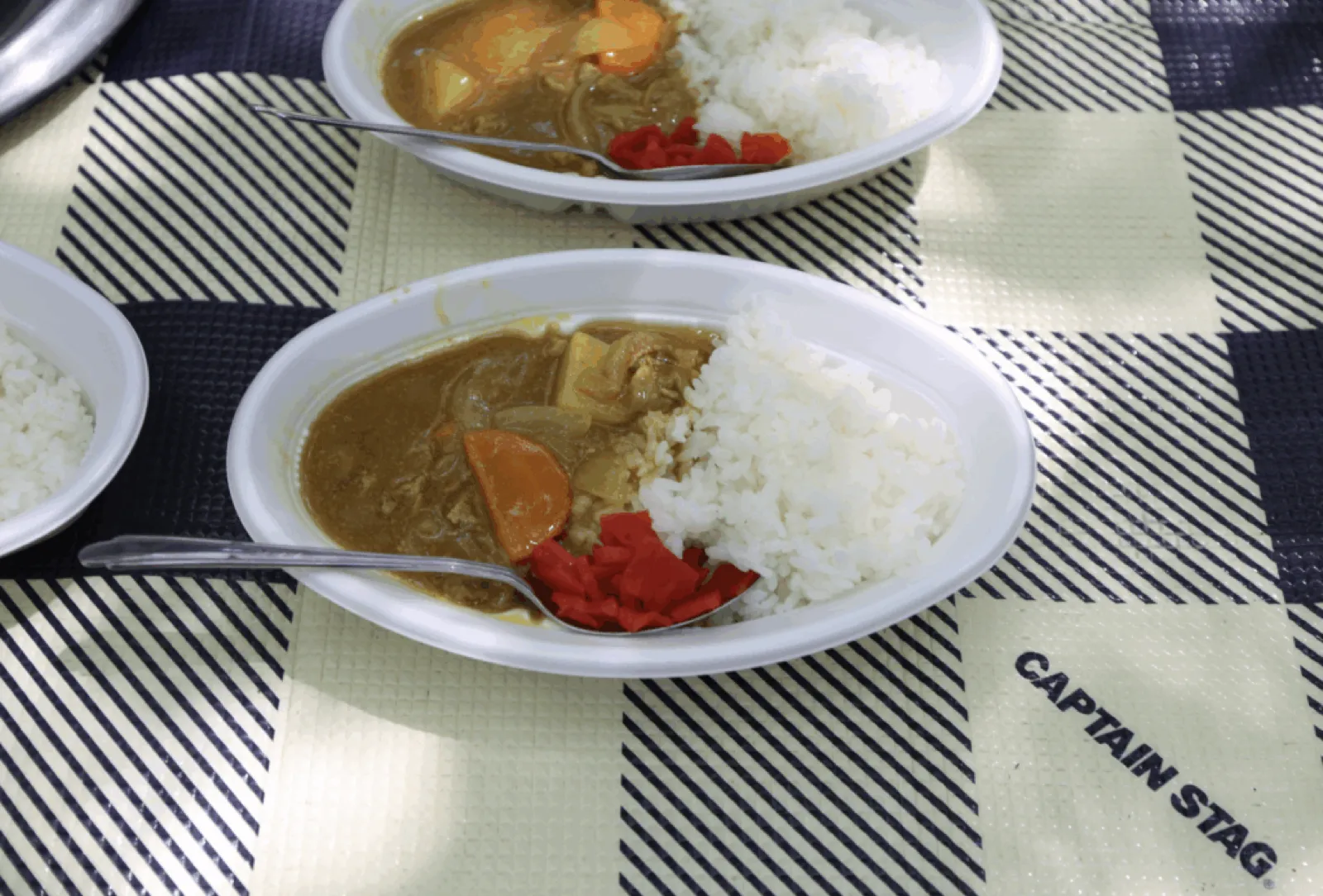 野外炊事で作ったカレーライス。白い皿に盛られ、福神漬けが添えてある。